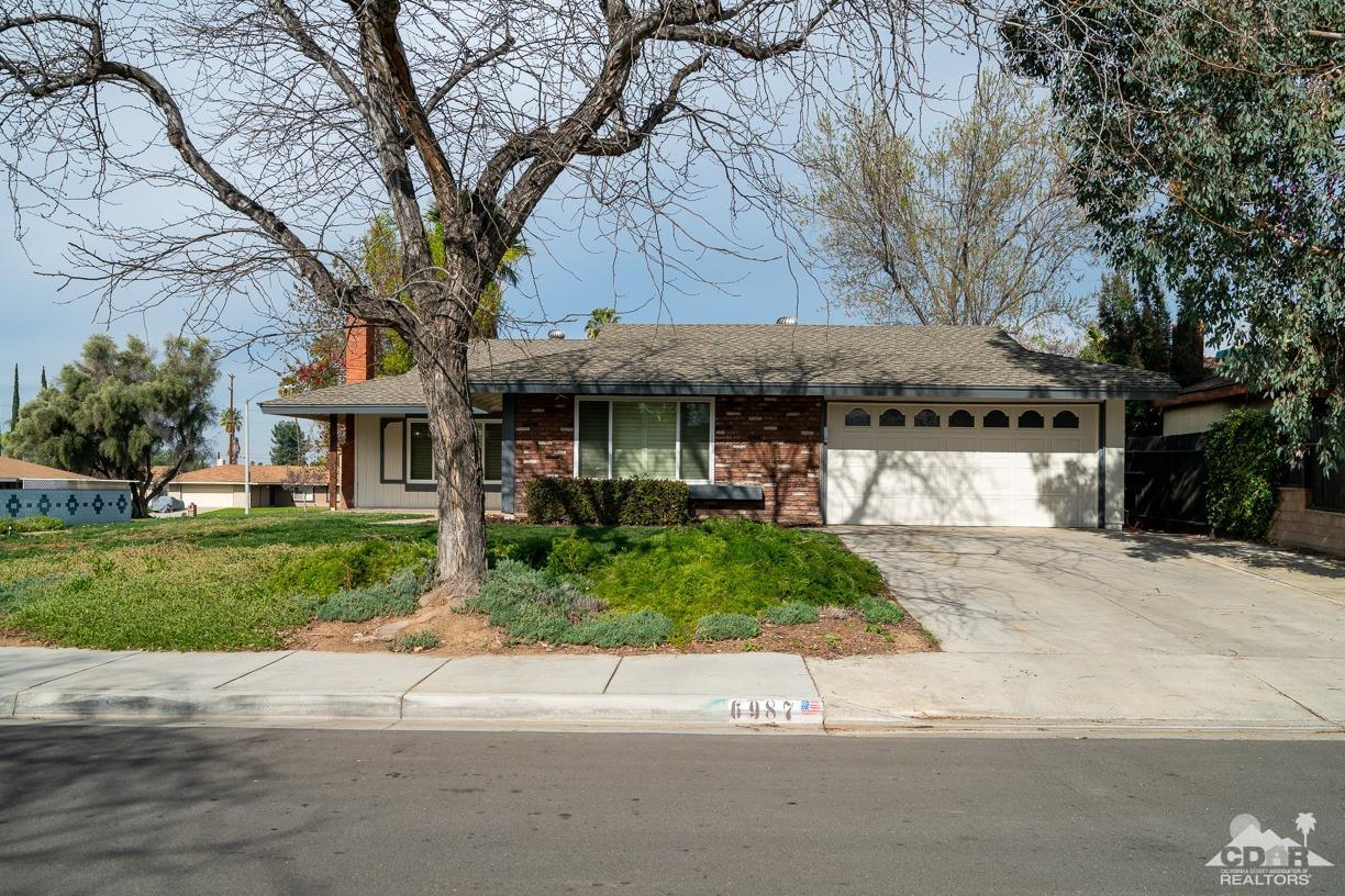6987 Manhattan Drive Riverside, CA 92506 - Photo 19 of 28 a front view of a house with a garden and trees