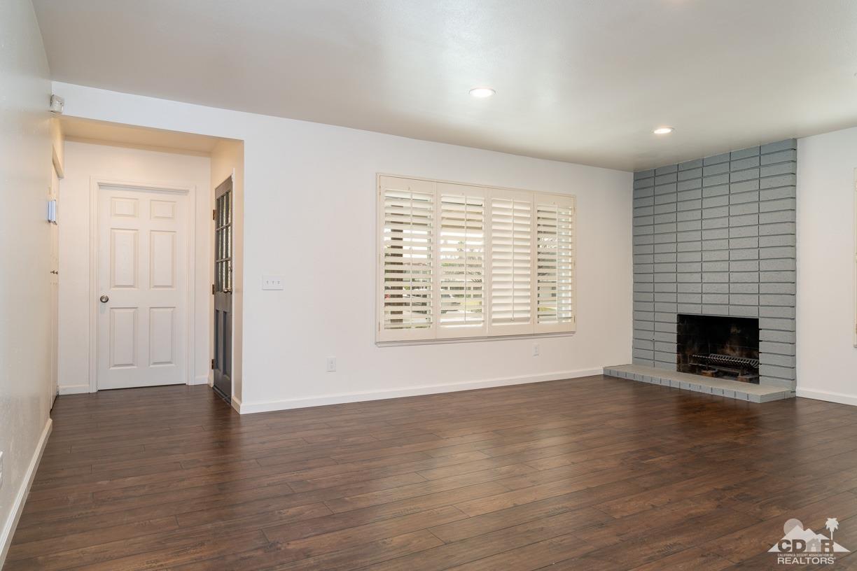 6987 Manhattan Drive Riverside, CA 92506 - Photo 5 of 28 an empty room with wooden floor a fireplace and windows