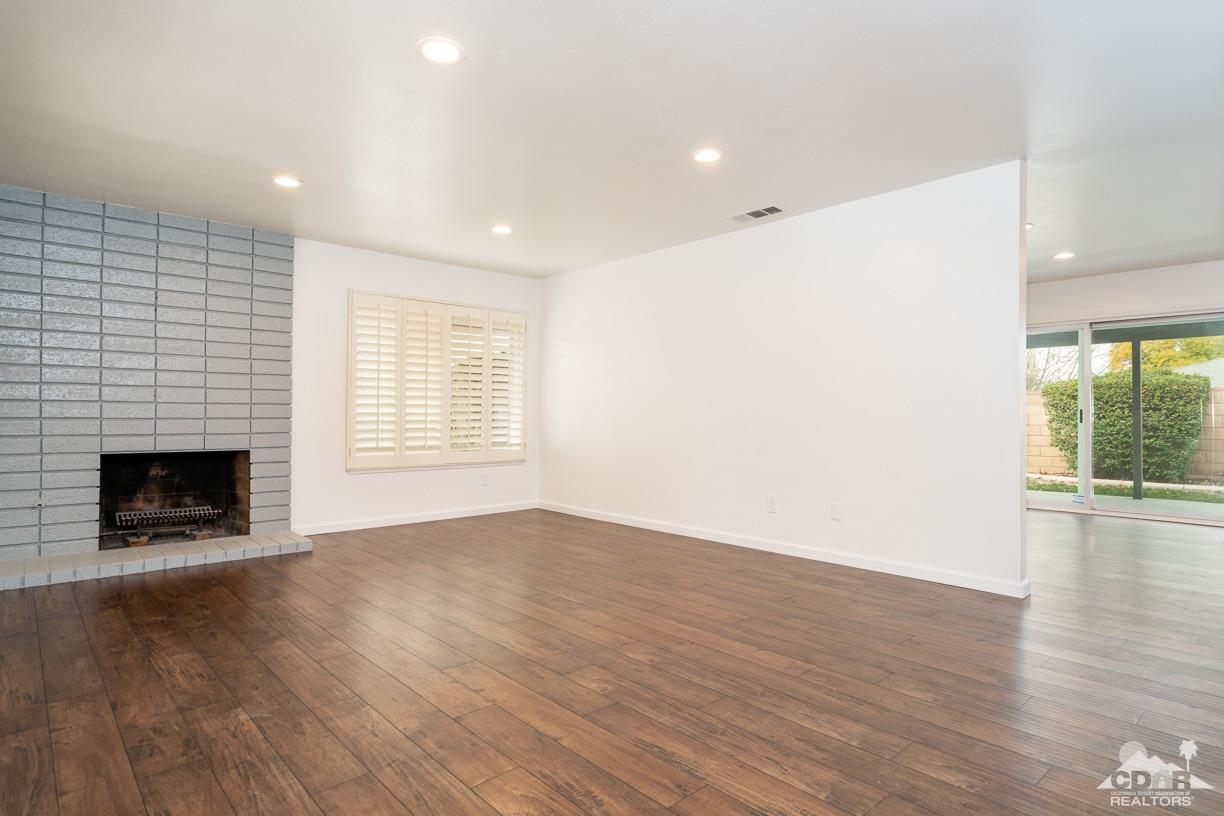 6987 Manhattan Drive Riverside, CA 92506 - Photo 7 of 28 an empty room with wooden floor fireplace and windows