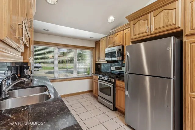 a kitchen with granite countertop a refrigerator a stove a sink and dishwasher