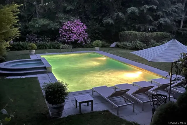 a view of a swimming pool with lawn chairs under an umbrella