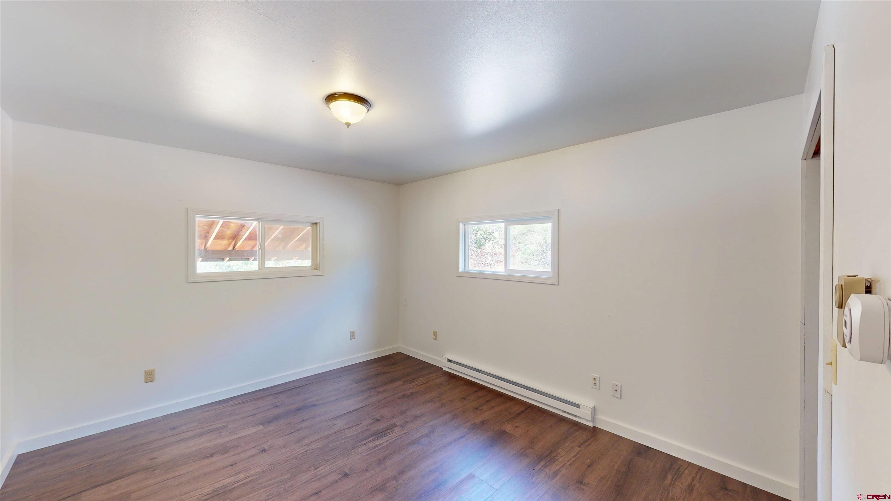 25615 Starner Loop Road Cedaredge, CO 81413 - Photo 15 of 42 an empty room with wooden floor and windows