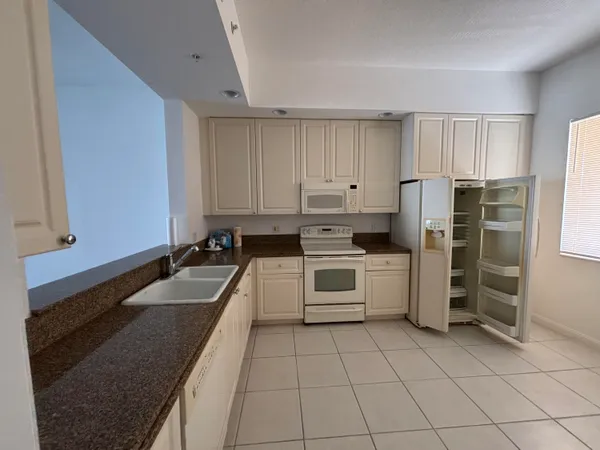 a large kitchen with a refrigerator sink and white cabinets