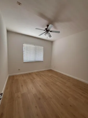 a view of an empty room with a chandelier fan and wooden floor