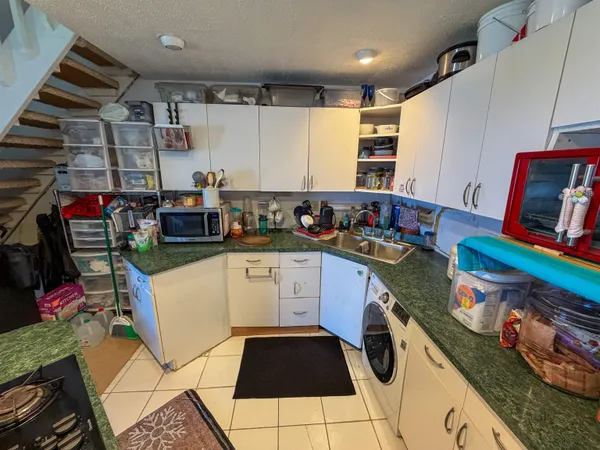 a kitchen with granite countertop lots of clutter and stainless steel appliances