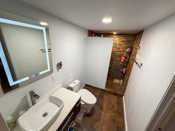 a bathroom with a sink and mirror with toilet