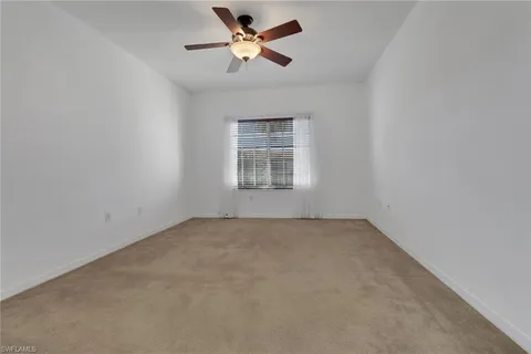 an empty room with a chandelier fan and a ceiling fan