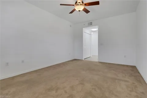 an empty room with a ceiling fan and window