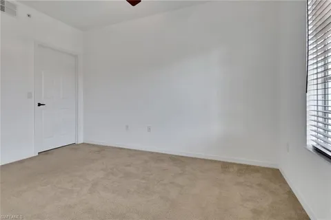 an empty room with a window and a ceiling fan