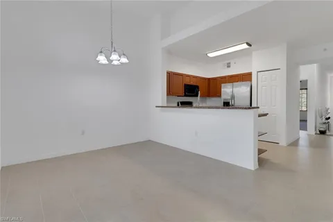 an empty room with chandelier fan and windows