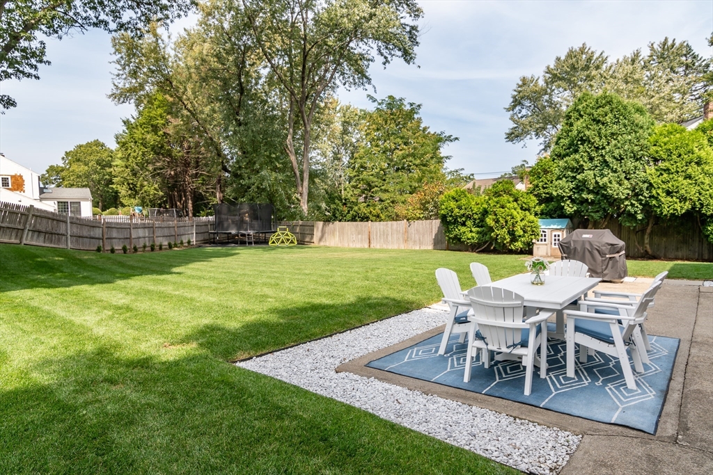 53 Bacon Street Natick, MA 01760 - Photo 27 of 30 a view of a backyard with table and chairs and potted plants and big trees