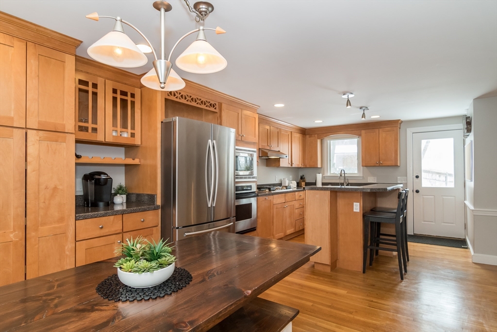 53 Bacon Street Natick, MA 01760 - Photo 8 of 30 a kitchen with stainless steel appliances granite countertop a refrigerator a stove a sink dishwasher and a dining table with wooden floor