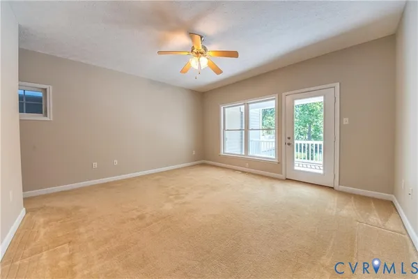 an empty room with windows and chandelier fan