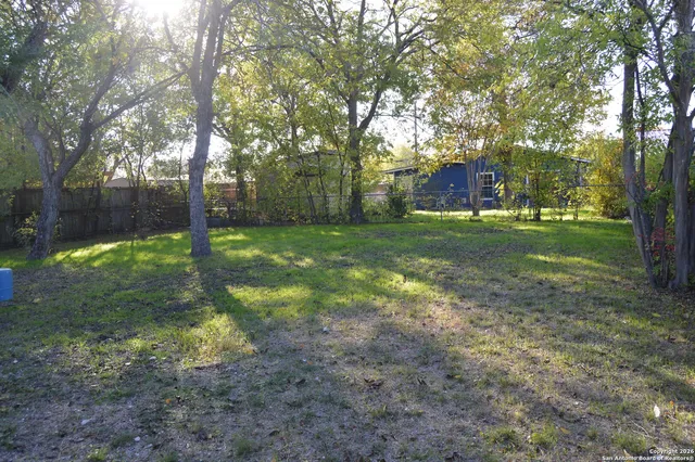 a view of a backyard with large trees and a small barn