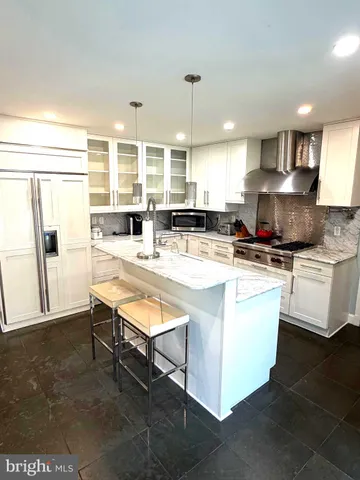 a kitchen with kitchen island granite countertop a stove a sink a refrigerator and white cabinets with wooden floor