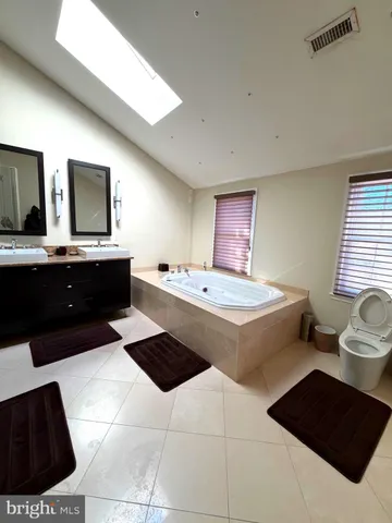 a spacious bathroom with a bathtub a sink and a large mirror