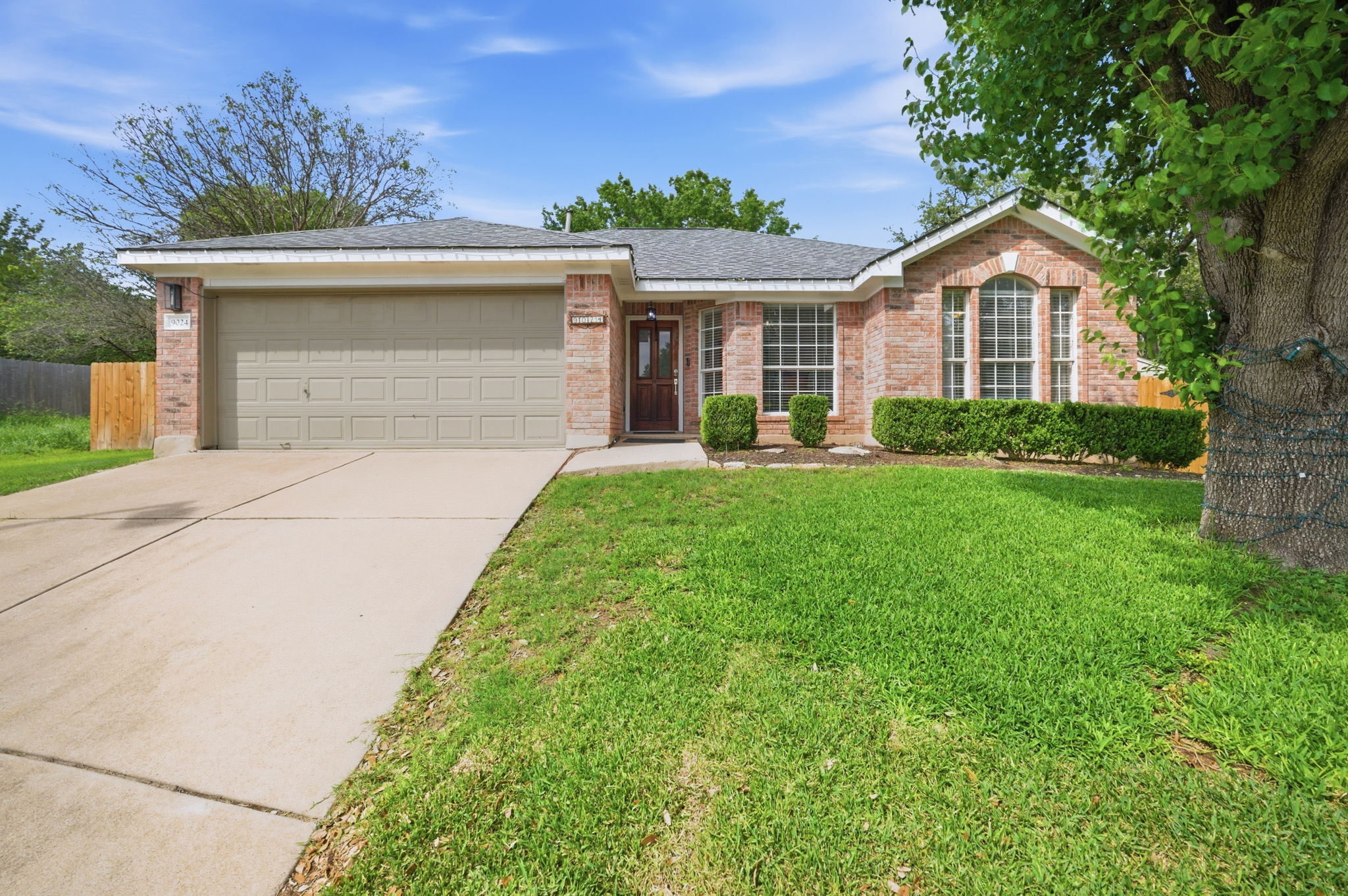 9024 Heiden Lane Austin, TX 78749 - Photo 2 of 28 Brick facade home with an attached garage, paved driveway, and established front landscaping