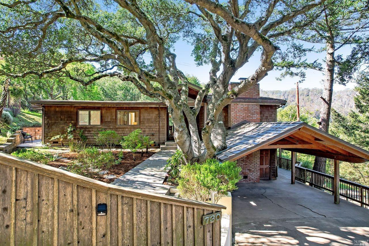 a view of a house with wooden fence next to a yard