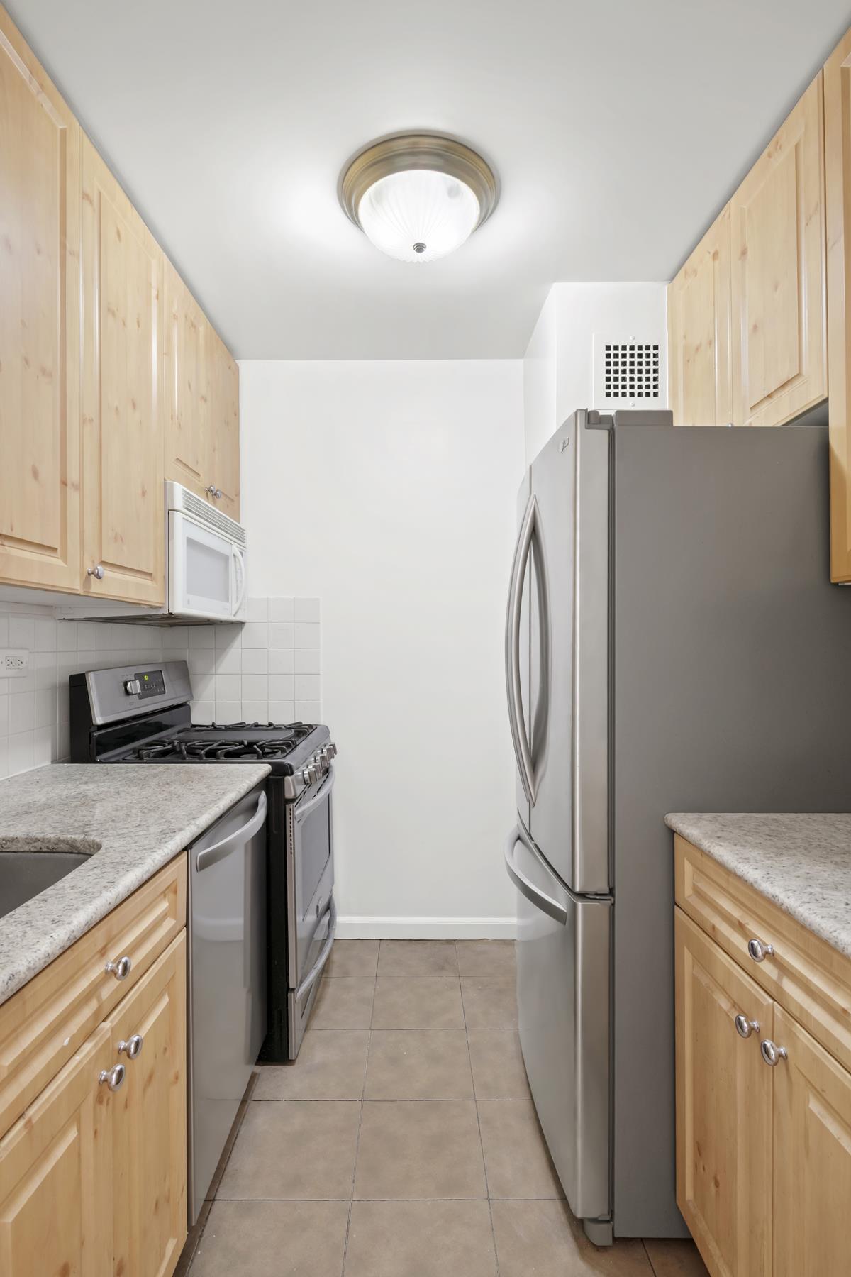 301 East 79th Street, Unit 15M Manhattan, NY 10075 - Photo 6 of 8 a kitchen with a stove top oven sink and cabinets