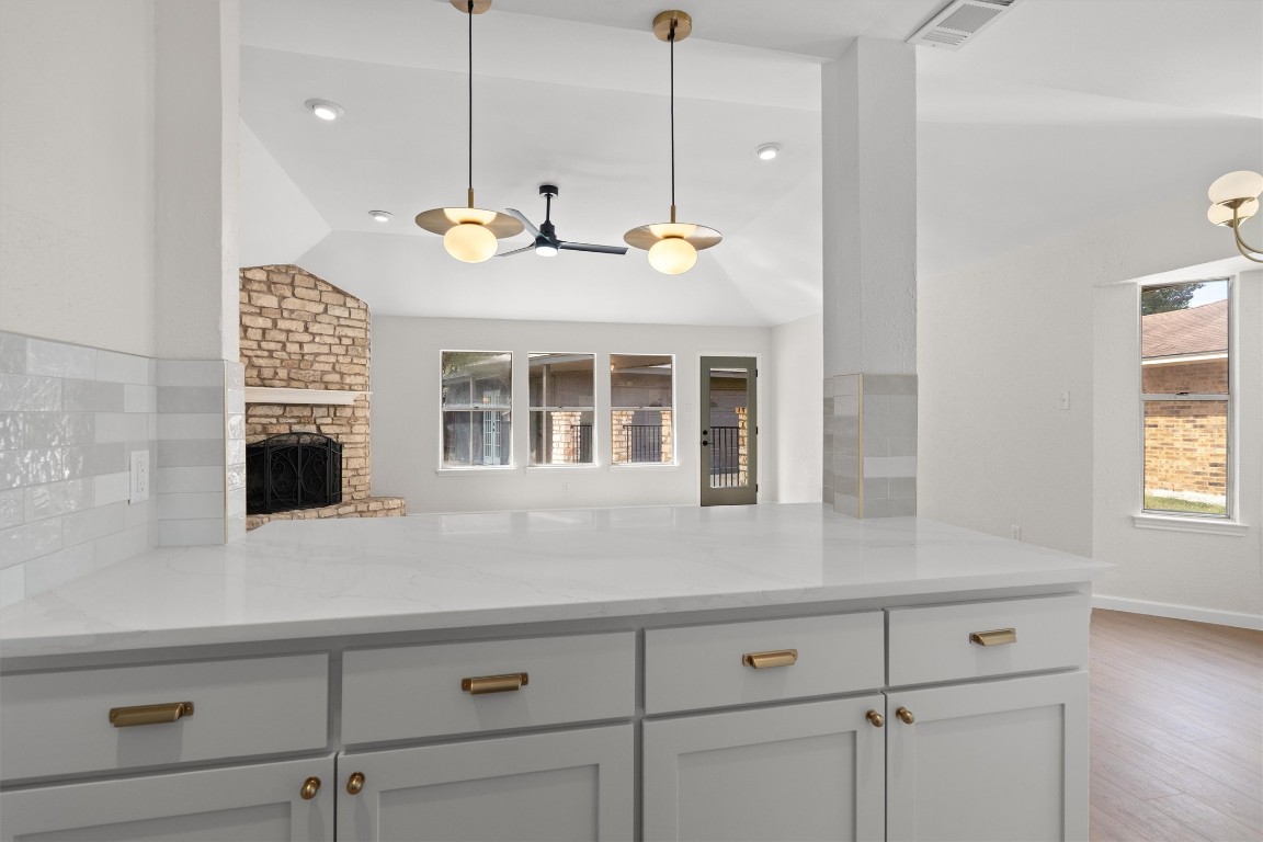 7008 Beckett Road Austin, TX 78749 - Photo 11 of 23 Kitchen with light stone counters, vaulted ceiling, healthy amount of natural light, a stone fireplace, and hanging light fixtures