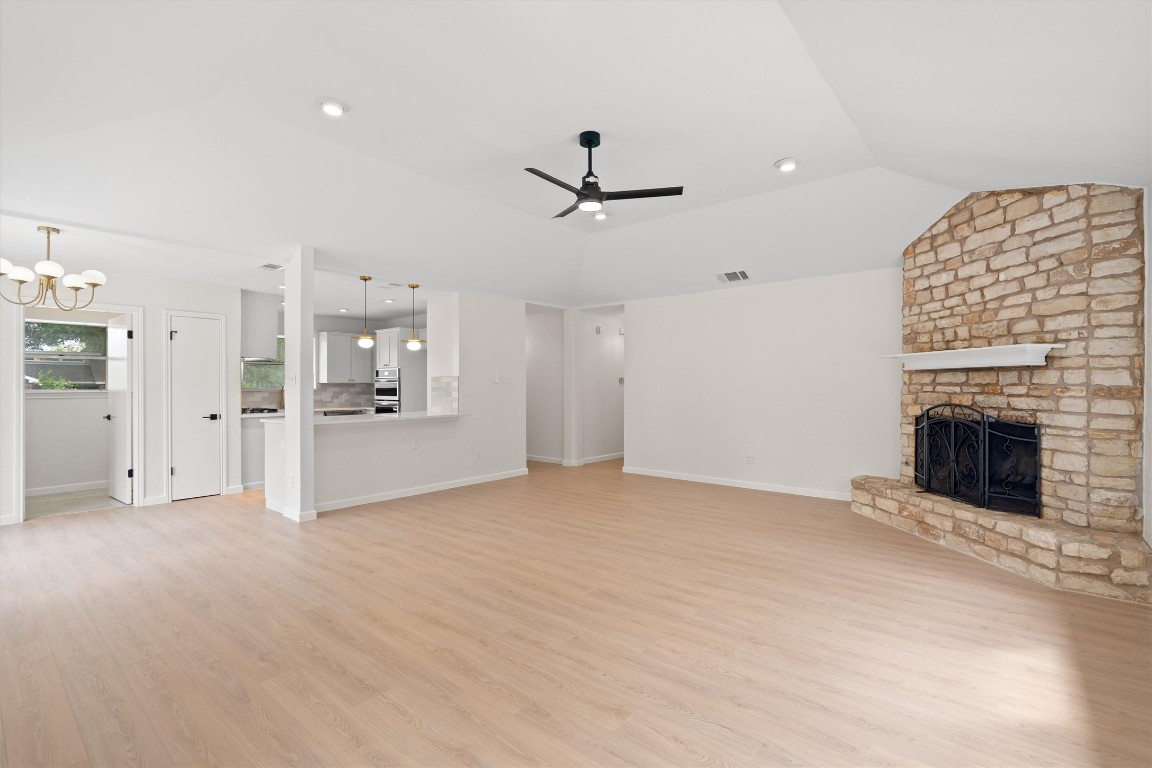 7008 Beckett Road Austin, TX 78749 - Photo 4 of 23 Unfurnished living room with light wood-style flooring, lofted ceiling, ceiling fan, a large fireplace, and recessed lighting
