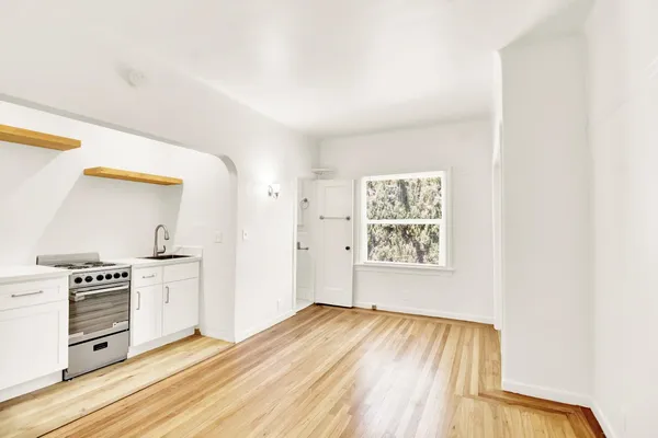 a view of a kitchen with wooden floor electronic appliances and windows