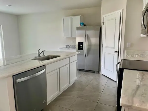 a kitchen with stainless steel appliances granite countertop a sink and a refrigerator