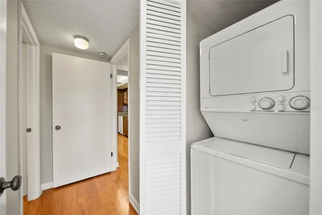 a view of an empty room with chandelier fan and wooden floor