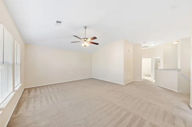 an empty room with a chandelier fan and wooden floor