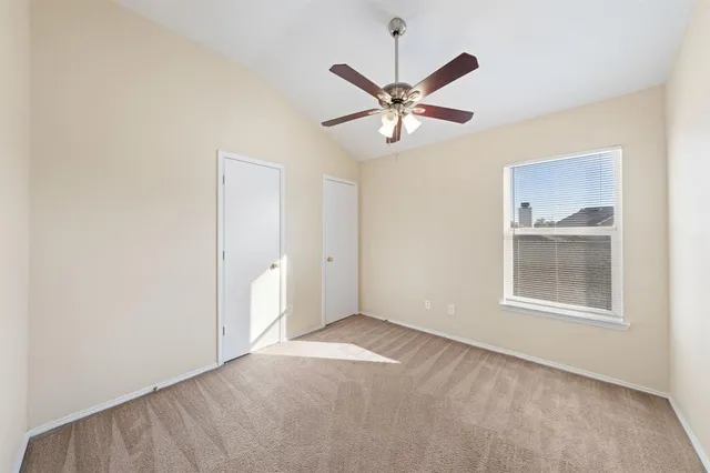 an empty room with windows and fan