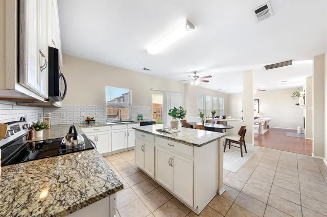 a kitchen with white cabinets and sink
