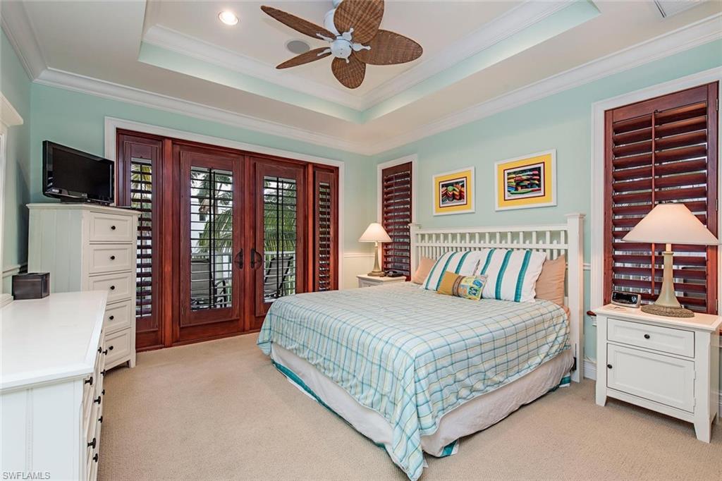 85 13th Avenue South Naples, FL 34102 - Photo 9 of 13 a bedroom with a large bed and a flat tv screen on dresser