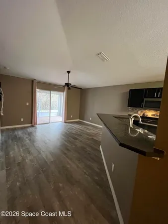 a kitchen with stainless steel appliances kitchen island granite countertop a refrigerator a stove top oven and a sink with wooden floor