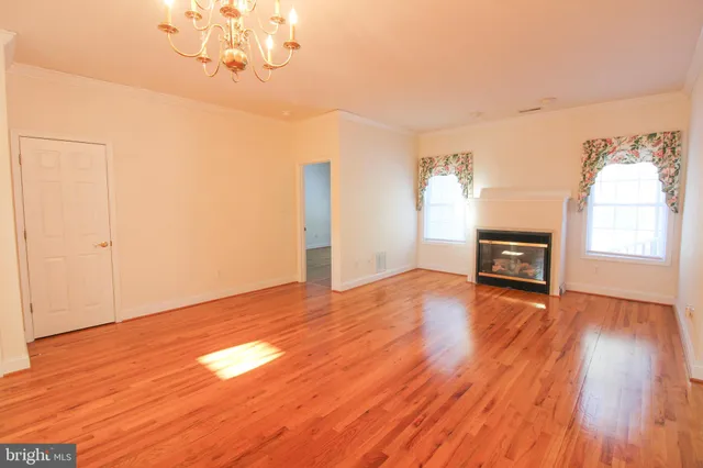 a view of a livingroom with wooden floor a chandelier and windows