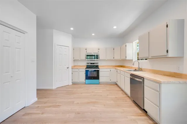 a kitchen with granite countertop white cabinets and stainless steel appliances