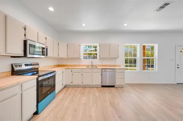 a kitchen with a sink wooden floor and stainless steel appliances