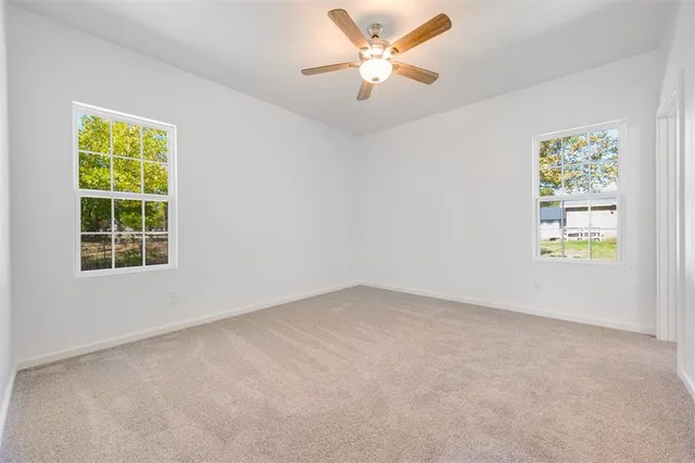 an empty room with windows and fan