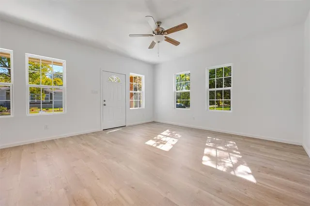 a view of an empty room with a window and wooden floor