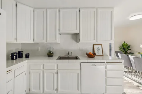 a kitchen with granite countertop a sink dishwasher stove and white cabinets