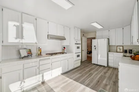 a kitchen with stainless steel appliances granite countertop a lot of counter space and wooden floors