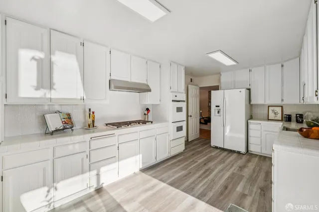 a kitchen with stainless steel appliances granite countertop a lot of counter space and wooden floors