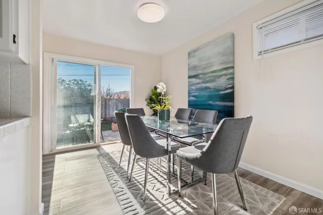 a view of a dining room with furniture a potted plant and wooden floor