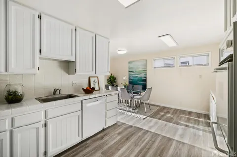 a kitchen with white cabinets and sink