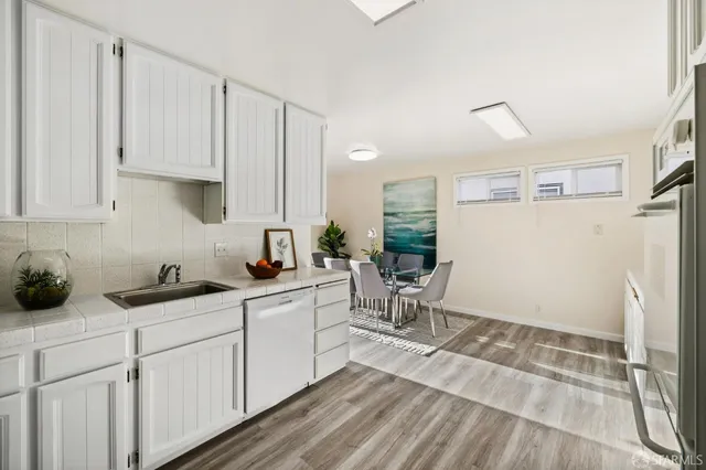 a kitchen with white cabinets and sink