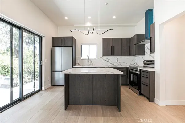 a kitchen with stainless steel appliances granite countertop a refrigerator a sink a stove and a wooden floors