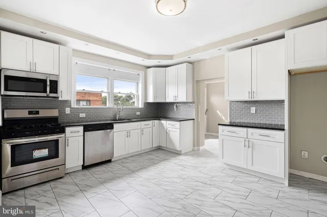 a kitchen with granite countertop a stove a sink and a microwave