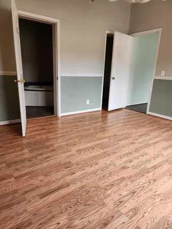 a view of an empty room with wooden floor and stairs