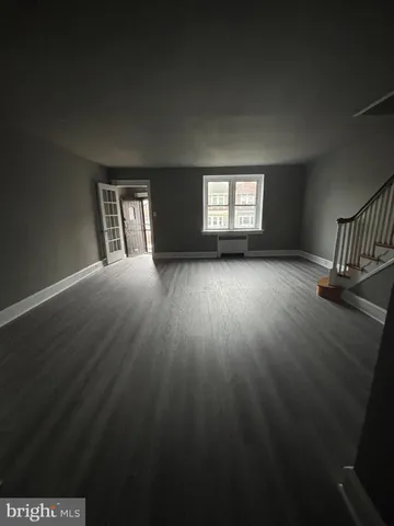a view of an empty room and wooden floor and window in a room
