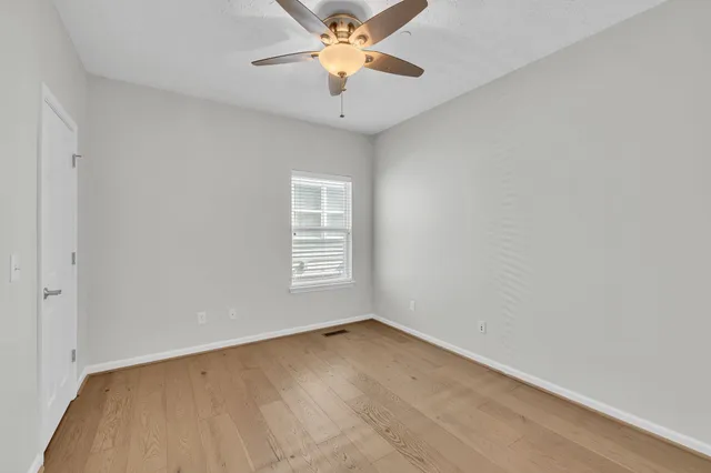 an empty room with a window and a ceiling fan