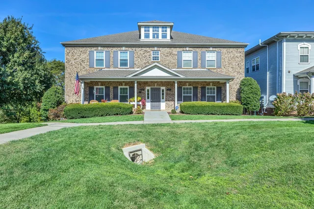 a front view of a house with garden and trees